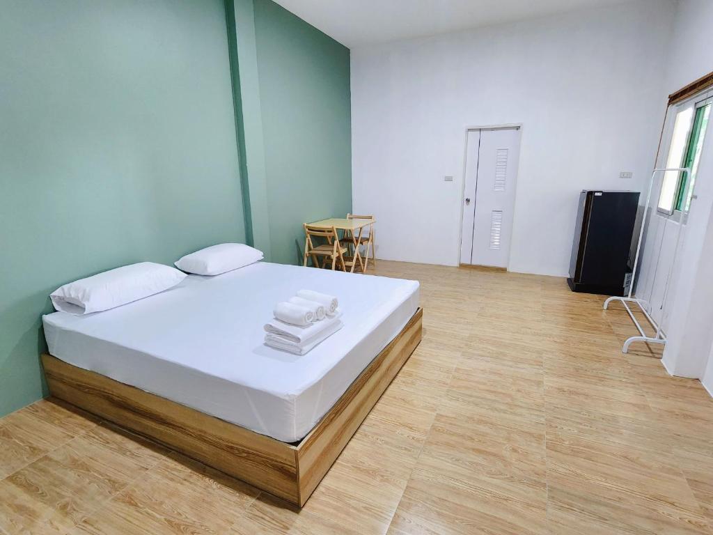 ห้องนอนสไตล์มินิมอลในรีสอร์ทชัยนาทที่มีเตียงคู่ พื้นไม้ ผนังสีเขียวมิ้นต์ โต๊ะตัวเล็กพร้อมเก้าอี้ และตู้เย็น ที่พักชัยนาท