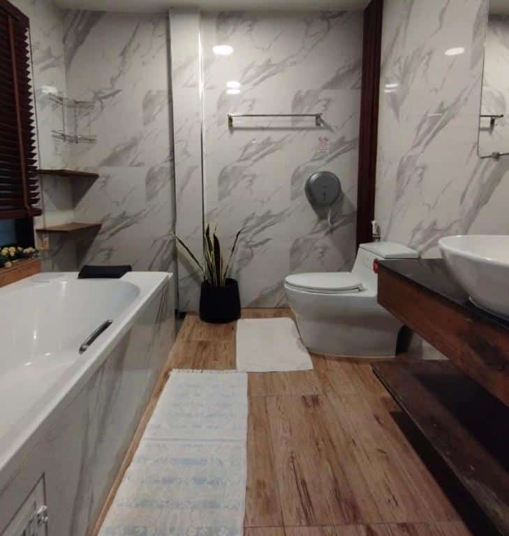ห้องน้ำทันสมัยผนังหินอ่อน โต๊ะเครื่องแป้งไม้พร้อมอ่างล้างหน้า 2 อ่าง อ่างอาบน้ำ และพรมปูพื้นลายที่ ชัยนาทรีสอร์ท