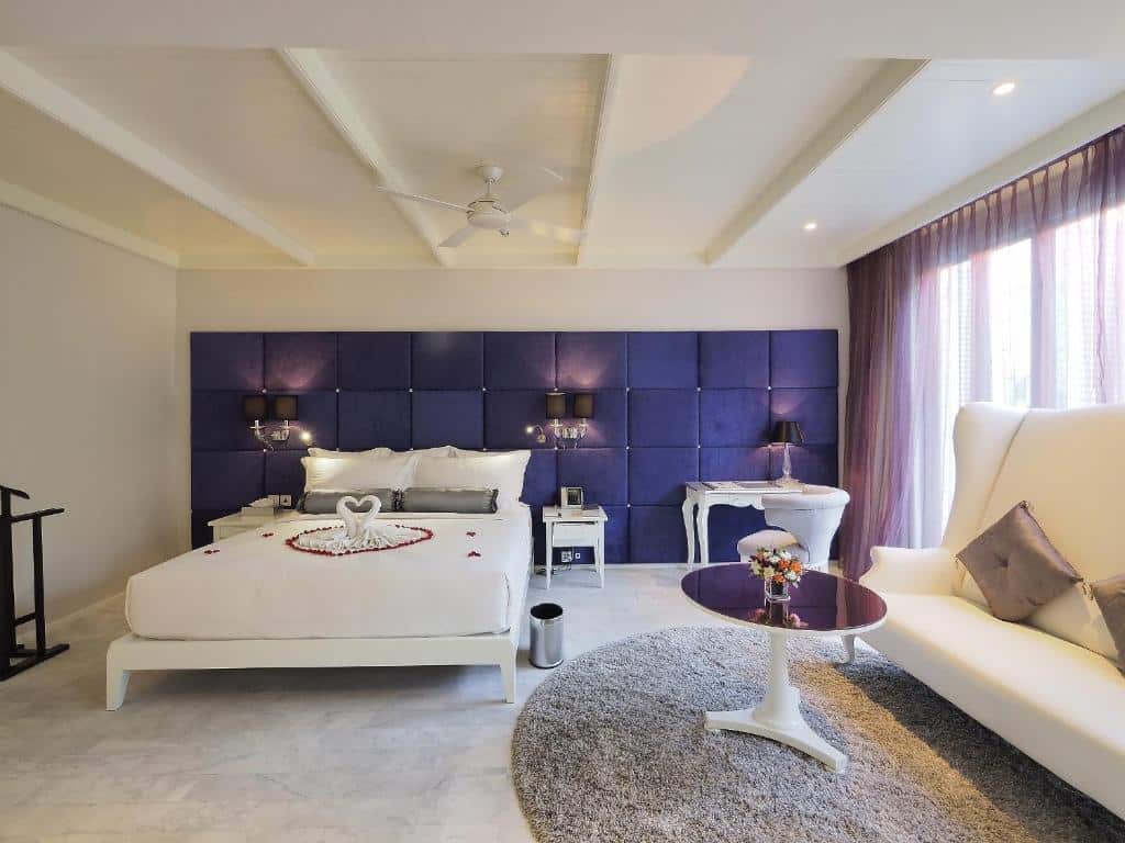 ห้องนอนกว้างขวางตกแต่งสไตล์โมเดิร์น มีเตียงสีขาวจัดเป็นรูปหัวใจ โซฟา  ที่พักใกล้กรุงเทพ และโต๊ะตัวเล็ก