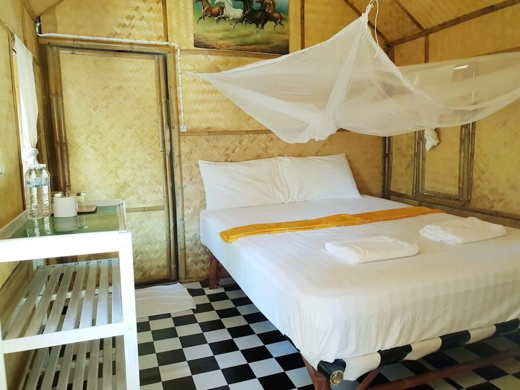 ภายในห้องนอนสไตล์ชนบทของเดอะบลูสกายรีสอร์ทเกาะพยามด้วยผนังไม้ไผ่ เตียงสีขาว พร้อมด้วย ที่พักเกาะพยาม