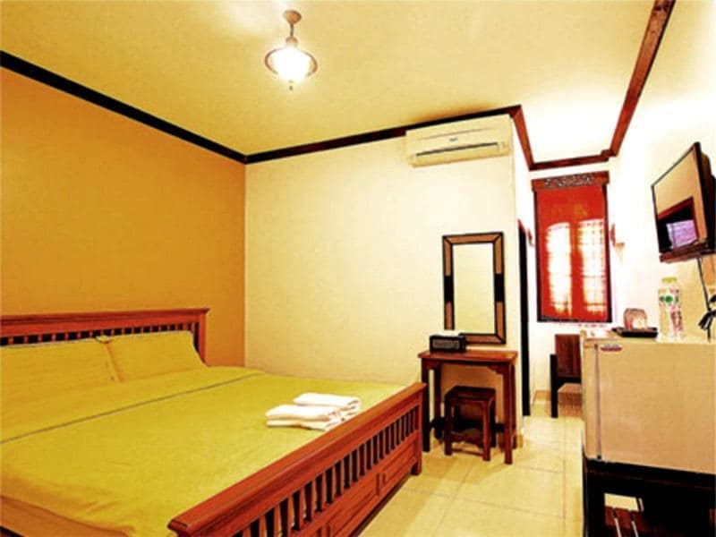 ห้องนอนตกแต่งอย่างเรียบง่ายพร้อมเตียงขนาดใหญ่ เฟอร์นิเจอร์ไม้ เครื่องปรับอากาศ และม่านสีแดงเหนือหน้าต่างที่มองเห็นแม่น้ำโขง ที่พักเชียงคานติดริมโขง