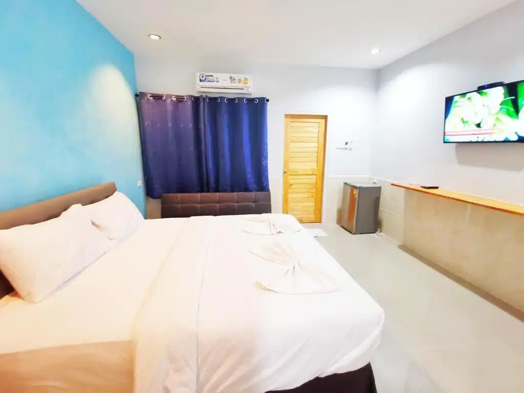 ห้องพักในโรงแรมที่สะอาดและทันสมัยมีเตียงขนาดใหญ่ ผ้าม่านสีฟ้า ทีวีติดผนัง และการตกแต่งที่เรียบง่ายที่หาดเตยงามที่สวยงาม หาดเตยงามที่พัก