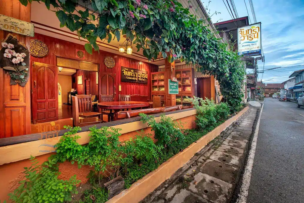 ร้านอาหารไทยแบบดั้งเดิมภายนอกตกแต่งด้วยไม้และต้นไม้สีเขียว ตั้งอยู่บนถนนที่เงี ที่พักเชียงคานติดริมโขง ยบสงบใกล้แม่น้ำโขงในเวลาพลบค่ำ
