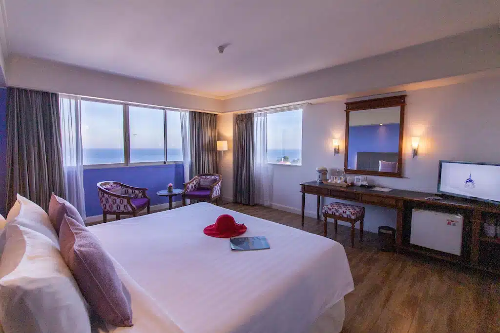 ห้องพักในโรงแรมพร้อมเตียงขนาดใหญ่ วิวทะเลผ่านหน้าต่าง เก้าอี้แบบดั้งเดิม โต๊ะเล็ก และทีวีในอียิปต์ โรงแรมหัวหิน