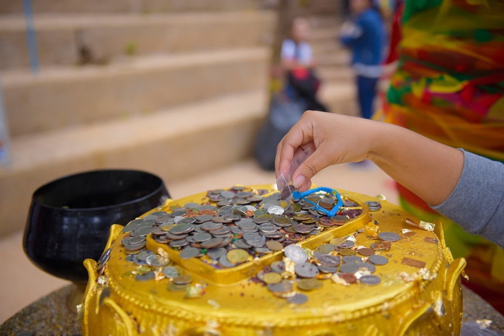 เด็กวางเหรียญบนแผ่นทองคำที่คลุมด้วยเหรียญอื่นตาม เขาคิชฌกูฏ ประเพณีหรือเครื่องบูชาที่เขาคิชฌกูฏ