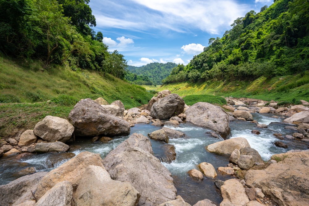 แม่น้ำอันเงียบสงบที่ไหลผ่านโขดหินในหุบเขาสีเขียวชอุ่ม ที่เที่ยวในกรุง ที่เที่ยวเดือนกรกฎาคม