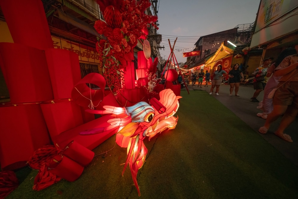 งานตรุษจีน โคมไฟมังกรสีสันสดใสที่ตลาดกลางแจ้งในช่วงเทศกาลตรุษจีน โดยมีนักช้อปเดินไปตามแผงขายของตอนพลบค่ำ