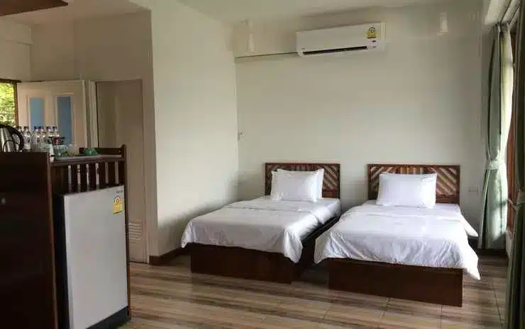 ที่พักฉะเชิงเทรา ภายในห้องพักโรงแรมเล็กๆ ในโรงแรมฉะเชิงเทรา มีเตียงเดี่ยว 2 เตียง พื้นไม้ ตู้เย็น และเครื่องปรับอากาศ