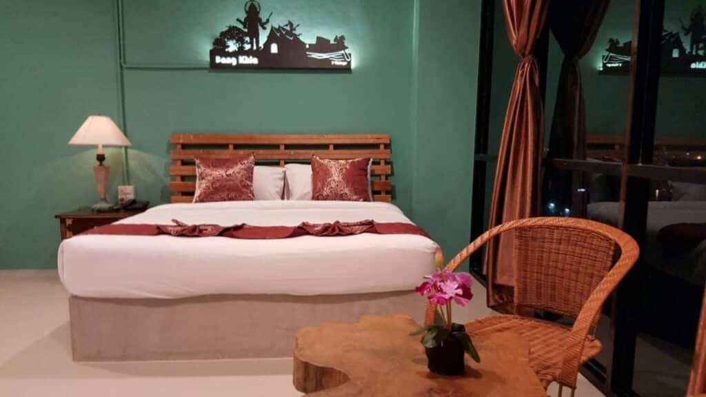 ที่พักฉะเชิงเทรา ห้องนอนทันสมัยพร้อมเตียงขนาดใหญ่ ผนังสีนกเป็ดน้ำ เฟอร์นิเจอร์ไม้อันเป็นเอกลักษณ์ และการตกแต่งด้วยศิลปะไทยในสไตล์ฉะเชิงเทรา