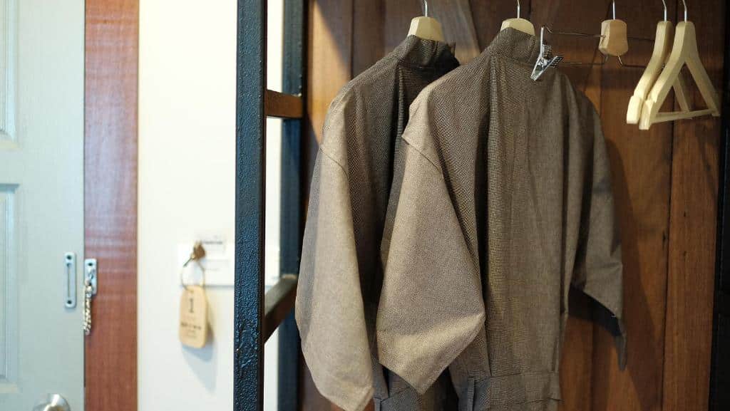 เสื้อแจ็คเก็ตผ้าทวีตสองตัวแขวนอยู่บนราวแขวนเสื้อข้างประตูในโรงแรมฉะเชิงเทรา โดยมีไม้แขวนเสื้อเปล่าและป้ายที่มองเห็นได้ ที่พักฉะเชิงเทรา