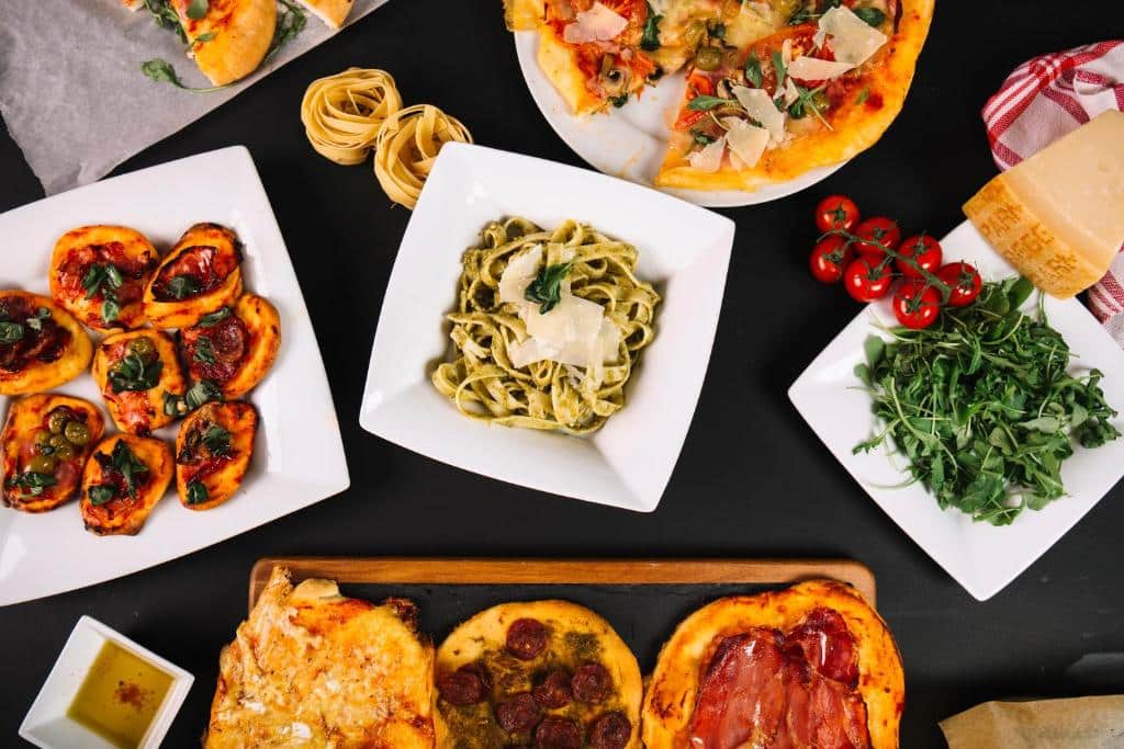 อาหารอิตาเลียนหลากหลายชนิด เช่น พิซซ่า พาสต้า และฟอคคาเซียเสิร์ฟบนโต๊ะ ต ที่พักพัทยา กแต่งด้วยสมุนไพรสดและเที่ยวน่านพริกไทย