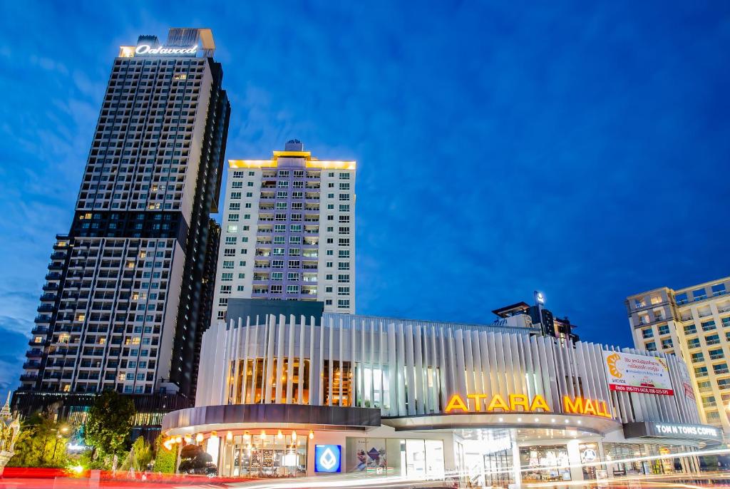 ทิวทัศน์ยามค่ำคืนของ Atara Mall และโรงแรมสูงระฟ้าที่อยู่ติดกันพร้อมภายนอกที่ส่องสว่างภายใต้ท้องฟ้ายามพลบค่ำ ตั้งอยู่ริมทะเลในศรีราชา ที่พักศรีราชาติดทะเล