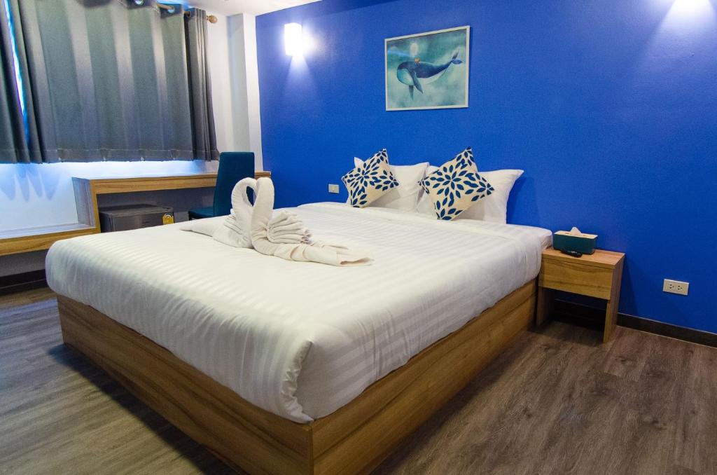 ห้องพักโรงแรมทันสมัยพร้อมเตียงคู่ขนาดใหญ่ ผนังสีฟ้า พื้นไม้ และผ้าเช็ดตัวประดับหงส์บนเตียงในเมืองน่าน ที่พักพัทยา