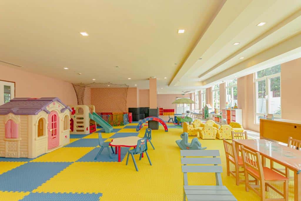 ห้องเด็กเล่นในร่มที่กว้างขวางและสว่างไสว พร้อมด้วยเครื่องเล่นสีสันสดใส โต๊ะ เก้าอี้ และพื้นเบาะรอครอบครัวที่มาพักที่โรงแรมหัวหินราคาถูก