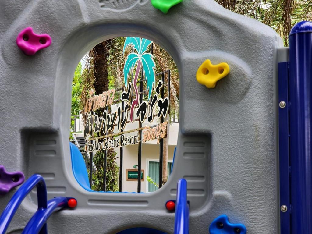 โครงสร้างสนามเด็กเล่นที่มีฐานวางเท้าสีสันสดใส มองเห็นป้าย Rachana Resort Tours อยู่ด้านหลัง ทำให้มองเห็นบ้านพักพูลวิลล่าจันทบุรีที่หรูหรา