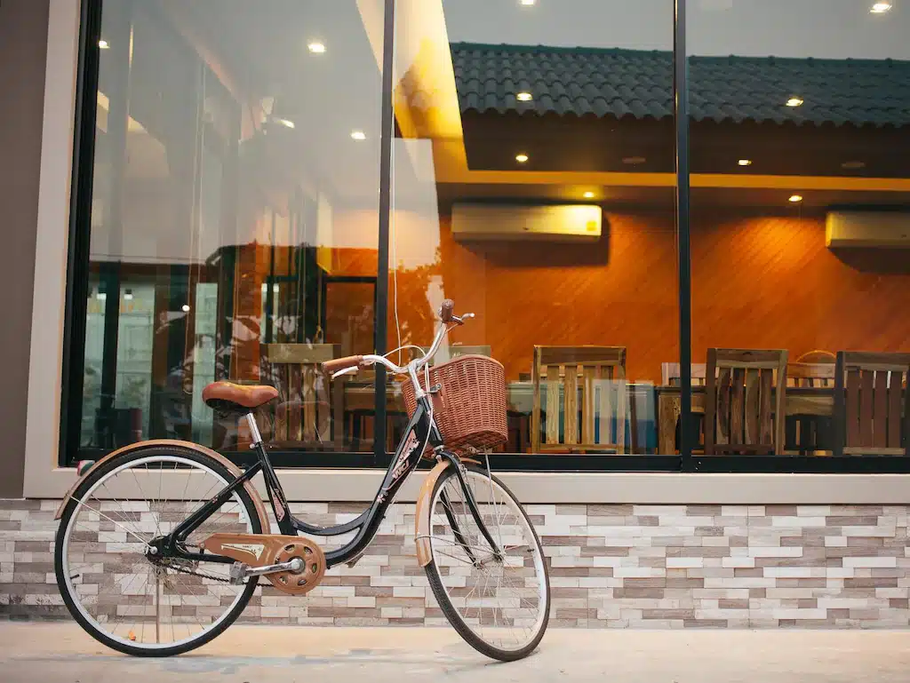 จักรยานวินเทจมีตะกร้าหน้าจอดอยู่นอกร้านกาแฟทันสมัยในเมืองน่าน หน้าต่างกระจกและเฟอร์นิเจอร์ไม้ ที่พักพัทยา