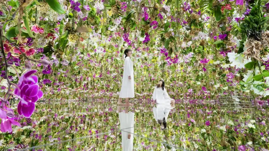 คนสองคนในชุดสีขาวยืนอยู่ท่ามกลางสวนแนวตั้งที่เต็มไปด้วยสีสันและหนาแน่นของดอกไม้นานาชนิดในมาเก๊า ที่เที่ยวมาเก๊า