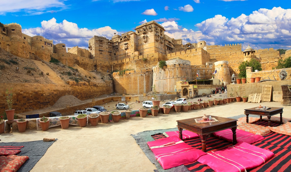 ทิวทัศน์ของป้อม Jaisalmer ภายใต้ท้องฟ้าสีคราม พร้อมที่นั่งแบบดั้งเดิมและเครื่องปั้นดินเผาที่แสดงอยู่เบื้องหน้าขณะท่องเที่ยวอินเดีย