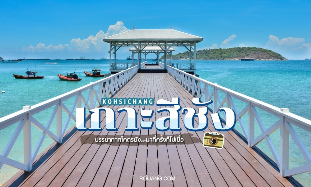 ท่าเรือไม้ทอดยาวออกไปสู่น้ำทะเลสีฟ้าคราม โดยมีเรือลำเล็กจอดอยู่ใกล้ๆ และมีเกาะที่เป็นเนินเขาอยู่ด้านหลัง "เกาะสีชัง" สถานที่ฮันนีมูนในไทย มีเขียนไว้อย่างเด่นชัดทั้งภาษาไทยและอังกฤษบนภาพ เผยให้เห็นถึงความงดงามอันงดงามแห่งนี้ในส่วนที่เป็นโฮนีมูนในไทย