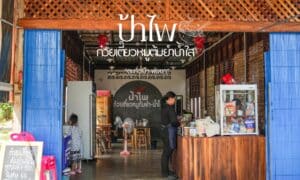 ร้านอาหารเล็กๆ ตกแต่งด้วยไม้ มีเคาน์เตอร์ ร้านอาหารตะกั่วป่า พร้อมตู้กระจก และมีแผงขายของอยู่ข้างในพร้อมป้าย "ป้าไฟก๋วยเตี๋ยวหมูต้มยำ" เป็นข้อความภาษาไทยด้านบน จะเห็นลูกค้ารับประทานอาหารอยู่ทางซ้ายมือ