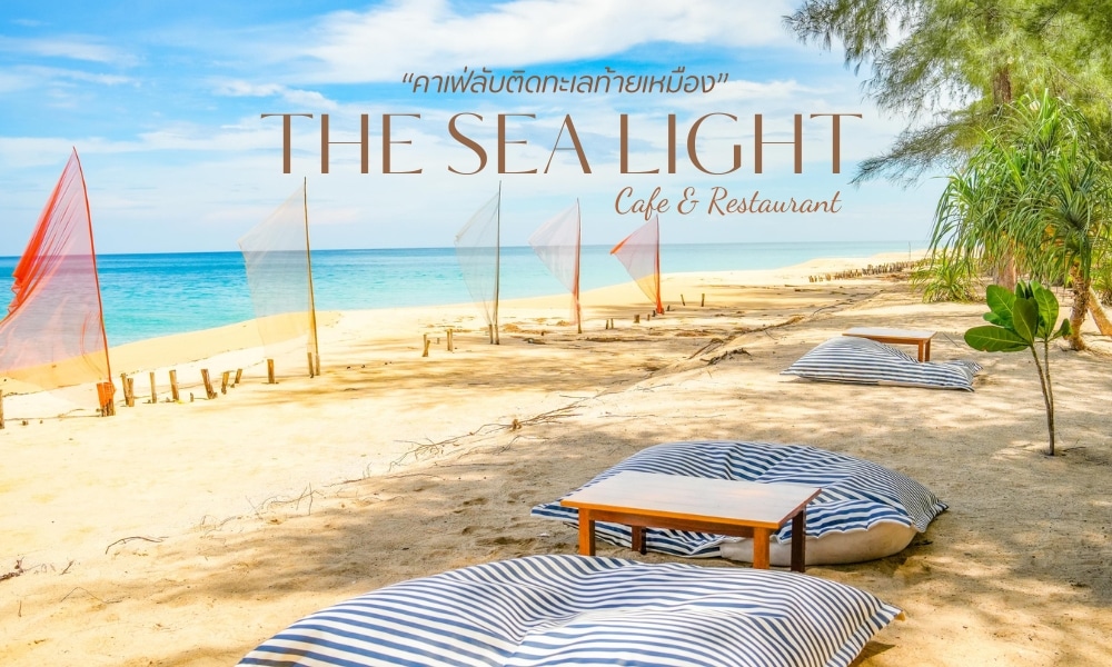คาเฟ่ริมชายหาดที่มีบีนแบ็กลายทาง โต๊ะไม้ และธงผ้าสีสันสดใส ป้ายเขียนว่า คาเฟ่พังงา "The Sea Light Cafe & Restaurant" ทั้งภาษาอังกฤษและภาษาไทย ทำให้ที่นี่เป็นจุดหมายปลายทางที่มีเสน่ห์สำหรับทั้งคนในพื้นที่และนักท่องเที่ยว