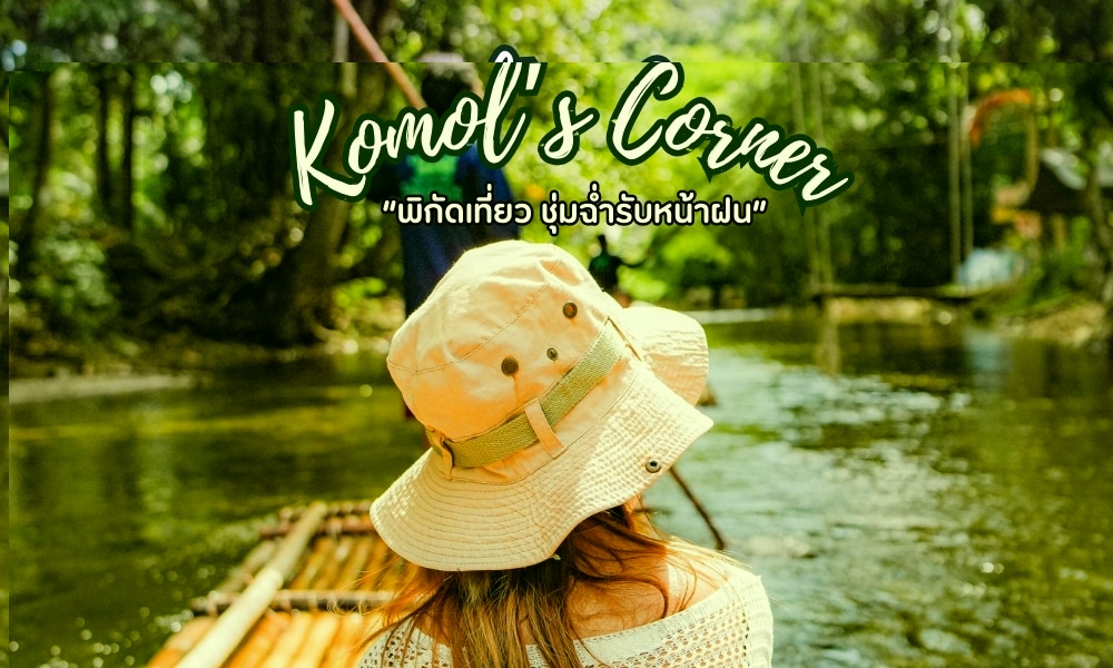 คนสวมหมวกนั่งบนแพลอยไปตามแม่น้ำที่รายล้อมไปด้วยต้นไม้เขียวขจี ข้อความด้านบนเขียนว่า "มุมโกมล" โดยมีข้อความเพิ่มเติมเป็นภาษาไทยด้านล่างและเรียกว่า " ที่เที่ยวพังงา "