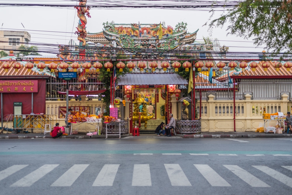 มุมมองถนนของทางเข้าวัดสว่างอารมณ์อันพลุกพล่าน วัดจีนที่ตกแต่งด้วยโคมไฟแขวนและทางม้าลายอยู่เบื้องหน้า วัดศาลเจ้าเซียนแปะโรงสี  วัดศาลเจ้า