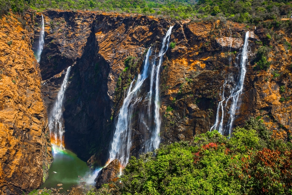 หุบเขาสูงชัน น้ำตกที่สวยที่สุดในโลก มีน้ำตกสูงหลายชั้นที่ลดหลั่นลงสู่สระน้ำเขียวขจีเบื้องล่าง ใบไม้หนาทึบตีกรอบด้านล่างของภาพ และมองเห็นสายรุ้งจางๆ ใกล้ผืนน้ำ ห่อหุ้มแก่นแท้ของน้ำตกในจินตนาการอย่างแท้จริง