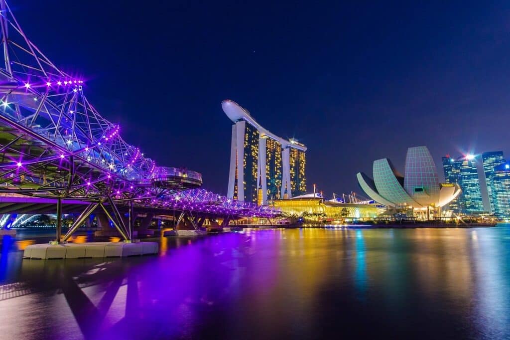 ทิวทัศน์ยามค่ำคืนของบริเวณ Marina Bay ของสิงคโปร์ โดยมีสะพาน Helix ที่ส่องสว่างเป็นสีม่วง ฮันนีมูน ที่ไหนดี โรงแรม Marina Bay Sands และพิพิธภัณฑ์ศิลปะและวิทยาศาสตร์ที่สะท้อนบนผิวน้ำ