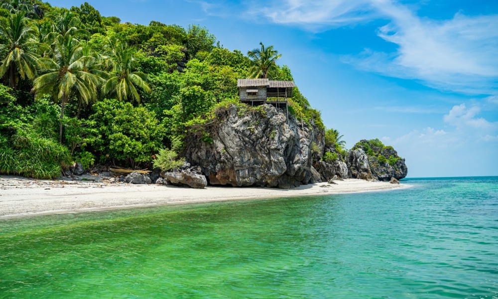 ชายหาดเขตร้อนอันเงียบสงบพร้อมน้ำทะเลสีฟ้าครามใส ทรายขาว ต้นไม้สีเขียวชอุ่ม และกระท่อมไม้เล็กๆ ทะเลใต้สวยๆ ที่ตั้งอยู่บนหน้าผาหินรอคอยผู้ที่มองหาเที่ยวทะเลภาคใต้และสัมผัสกับความงามของทะเลใต้ที่สวยงาม