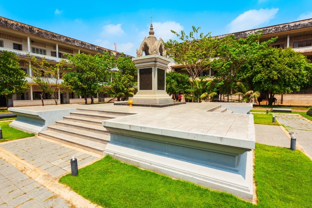 โครงสร้างอนุสรณ์บนพื้นยกสูงในลานที่ล้อมรอบด้วยแมกไม้เขียวขจีและอาคารสูงหลายชั้น สถานที่เที่ยวกัมพูชา เป็นองค์ประกอบที่โดดเด่นของกระดาษแข็งที่เที่ยว ทำให้ผู้มาเยือนเป็นสถานที่อันเงียบสงบสำหรับการไตร่ตรองท่ามกลางสภาพแวดล้อมที่คึกคัก