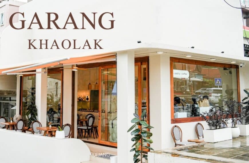 ทัศนียภาพถนนอันมีเสน่ห์ของ Garang Khaolak เผยให้เห็นร้านกาแฟที่แสนอบอุ่น ซึ่งมีหน้าต่างบานใหญ่ กระถางต้นไม้ที่เขียวชอุ่ม และที่นั่งกลางแจ้งที่น่าเชิญชวนที่ตั้งอยู่ในมุมถนนที่มีชีวิตชีวา