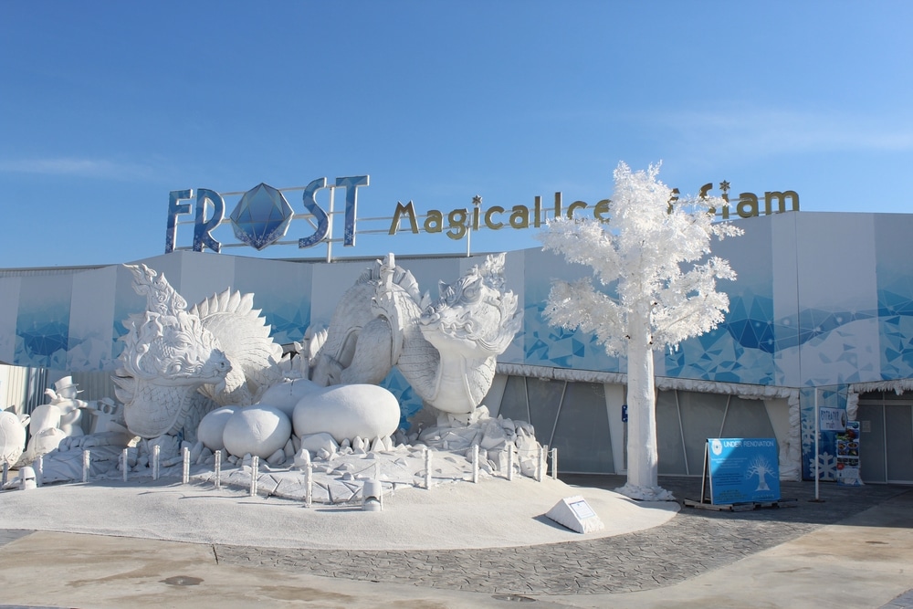 ทางเข้า "Frost Magical Ice of Siam" ที่ซึ่งประติมากรรมมังกรขาวขนาดใหญ่และต้นไม้น้ำแข็งยืนตระหง่านตัดกับท้องฟ้าสีครามที่สดใส ทำให้เกิดประสบการณ์ที่เที่ยวหน้าฝนโรแมนติกสำหรับนักท่องเที่ยวที่แสวงหามนต์เสน่ห์และความมหัศจรรย์ ไปเที่ยวกับครอบครัว