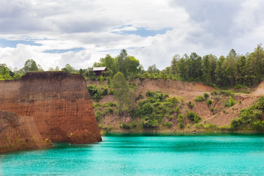 ทะเลสาบสีฟ้าคราม ทุ่งไฮเดรนเยีย ที่มีชีวิตชีวา เหมาะสำหรับเที่ยวหน้าฝนใกล้กรุงเทพ ล้อมรอบด้วยหน้าผาสูงชันที่ปกคลุมไปด้วยสีเขียวภายใต้ท้องฟ้าที่มีเมฆมาก