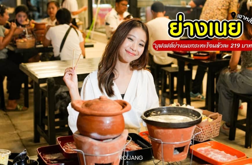 ผู้หญิงกำลังยิ้มอยู่ที่โต๊ะพร้อมอาหารและหม้อดินเผา ภาพร้านอาหารปรากฏให้เห็นในพื้นหลัง ข้อความในภาพเป็นภาษาไทย.