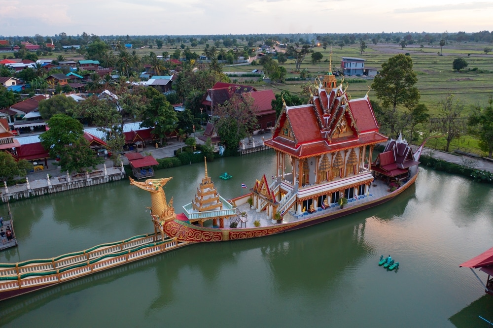 อาคารวัดที่มีลวดลายวิจิตรสวยงาม วัดที่สวยที่สุดในประเทศไทย คล้ายเรือที่ล่องไปตามน้ำ ล้อมรอบไปด้วยต้นไม้และทัศนียภาพชนบท เป็นสถานที่เงียบสงบสำหรับผู้มาเยือนที่สามารถเข้าไปสักการะที่วัดพระนอน.