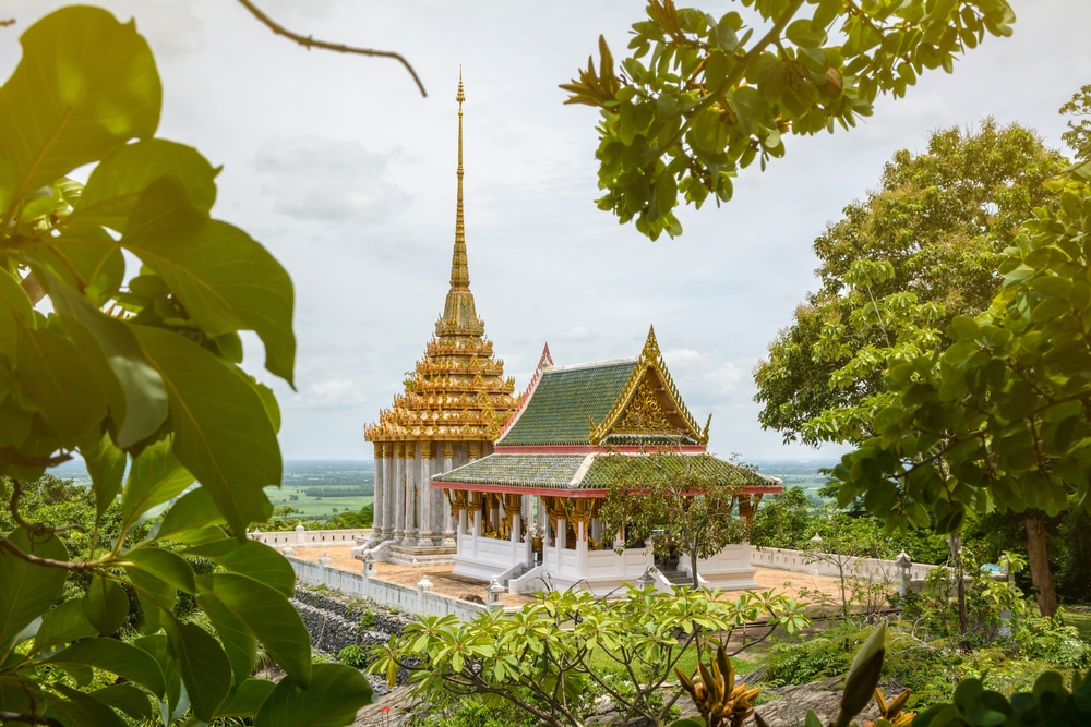 วัดหลังคาสี รอยพระพุทธบาท ทองสะท้อนถึงแก่นแท้ของรอยพระพุทธบาท มีรายละเอียดที่ซับซ้อน และล้อมรอบด้วยต้นไม้เขียวขจีใต้ท้องฟ้าที่มีเมฆมาก