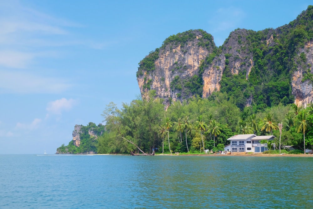 ค้นพบบรรยากาศชายฝั่งทะเลอันเงียบสงบ ที่เที่ยวตรัง ของบ้านริมน้ำ ท่ามกลางต้นปาล์มและหน้าผาอันเขียวชอุ่มภายใต้ท้องฟ้าสีครามสดใส หลีกหนีจากความวุ่นวายสำหรับผู้ที่แสวงหาความเงียบสงบในที่เที่ยวจังหวัดชุมพร.