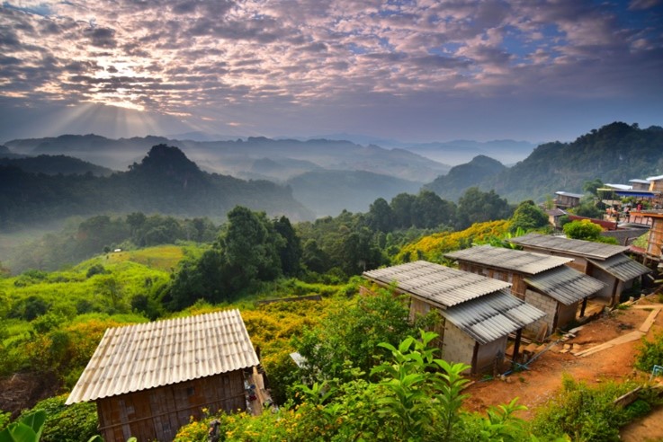 ทัศนียภาพอันงดงามของทิวเขาในไร่กาแฟ ภาคเหนือ เต็มไปด้วยกระท่อมไม้กระจัดกระจายและต้นไม้เขียวขจีใต้ หมู่บ้านสวยในไทย ท้องฟ้าน่าทึ่งที่แสงอาทิตย์สาดส่องผ่านเมฆมา.