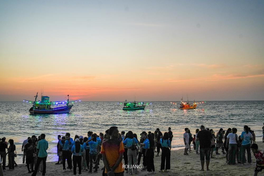 ในงานปล่อยเต่าท้ายข้อความในปี 2568 ผู้คนมารวมตัวกันบนชายหาดยามพระอาทิตย์ตกดิน ตื่นตาตื่นใจไปกับเรือสามลำที่ส่องสว่างแล่นข้ามทะเลอย่างสง่างาม.