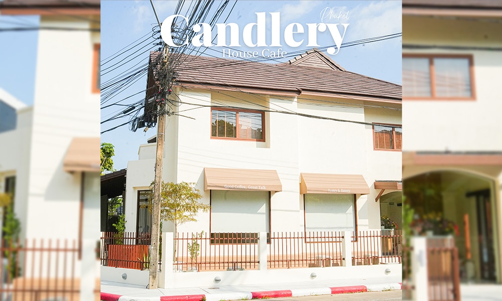 ร้าน Candlery House Cafe เป็นอาคารสองชั้นที่มีเสน่ห์ มีภายนอกที่สว่างไสว มีกันสาดเหนือหน้าต่างบานใหญ่ และล้อมรอบด้วยรั้วไม้และสายไฟฟ้าที่สวยงาม ให้บรรยากาศที่อบอุ่นสำหรับผู้ที่มาเยี่ยมชมทุกคน.