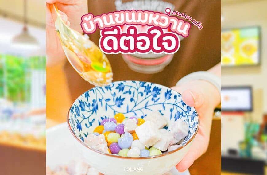 ที่บ้านขนมหวาน มีคนเสิร์ฟของหวานหลากสีสันที่ตกแต่งด้วยท็อปปิ้งทรงกลมเล็กๆ ในชามสีน้ำเงินและสีขาว บรรยากาศภายในอาคารที่พร่ามัวช่วยเพิ่มเสน่ห์ ขณะที่ป้ายบอกเป็นนัยถึงจุดที่น่ารื่นรมย์ในภูเก็ตซึ่งดีต่อใจอย่างแท้จริง.