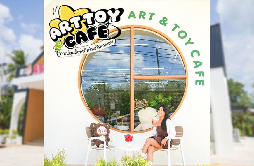 ผู้หญิงคนหนึ่งกำลังจิบเครื่องดื่มอยู่หน้า Art & Toy Cafe ซึ่งอยู่ข้างๆ ตุ๊กตาหุ่นของเล่นที่ตั้งตังค์ โลโก้ของร้านตั้งตระหง่านอยู่เบื้องหลัง.