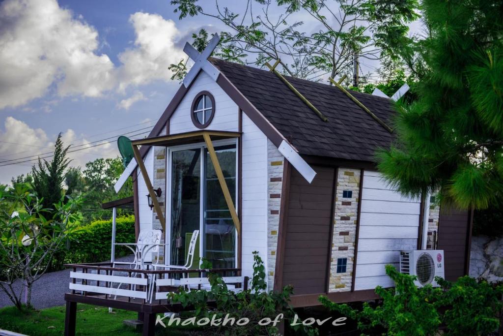 กระท่อมหลังเล็กๆ สไตล์โมเดิร์น พร้อมเครื่องปรับอากาศ ระเบียงรั้ว และที่นั่งกลางแจ้ง รายล้อมไปด้วย เขาค้อที่พัก ต้นไม้สีเขียวภายใต้ท้องฟ้าที่มีเมฆบางส่วน เหมาะสำหรับผู้ที่ต้องการพักหาดเจ้าหลาวในบรรยากาศเงียบสงบและเป็นธรรมชาติ.