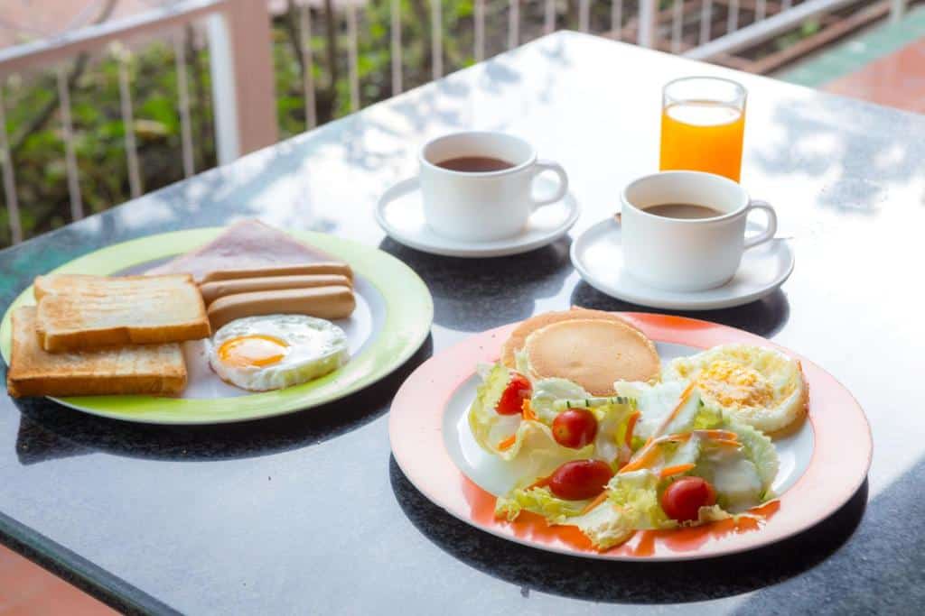 อาหารเช้า 2 จานพร้อมขนมปังปิ้ง ไข่ สลัด และแพนเค้ก พร้อมด้วยกาแฟหรือชา 2 แก้ว และน้ำส้มบนโต๊ะ  ที่พักเขาค้อ เหมาะอย่างยิ่งสำหรับเริ่มต้นวันใหม่ก่อนออกสำรวจ ที่พักหาดเจ้าหลาว.