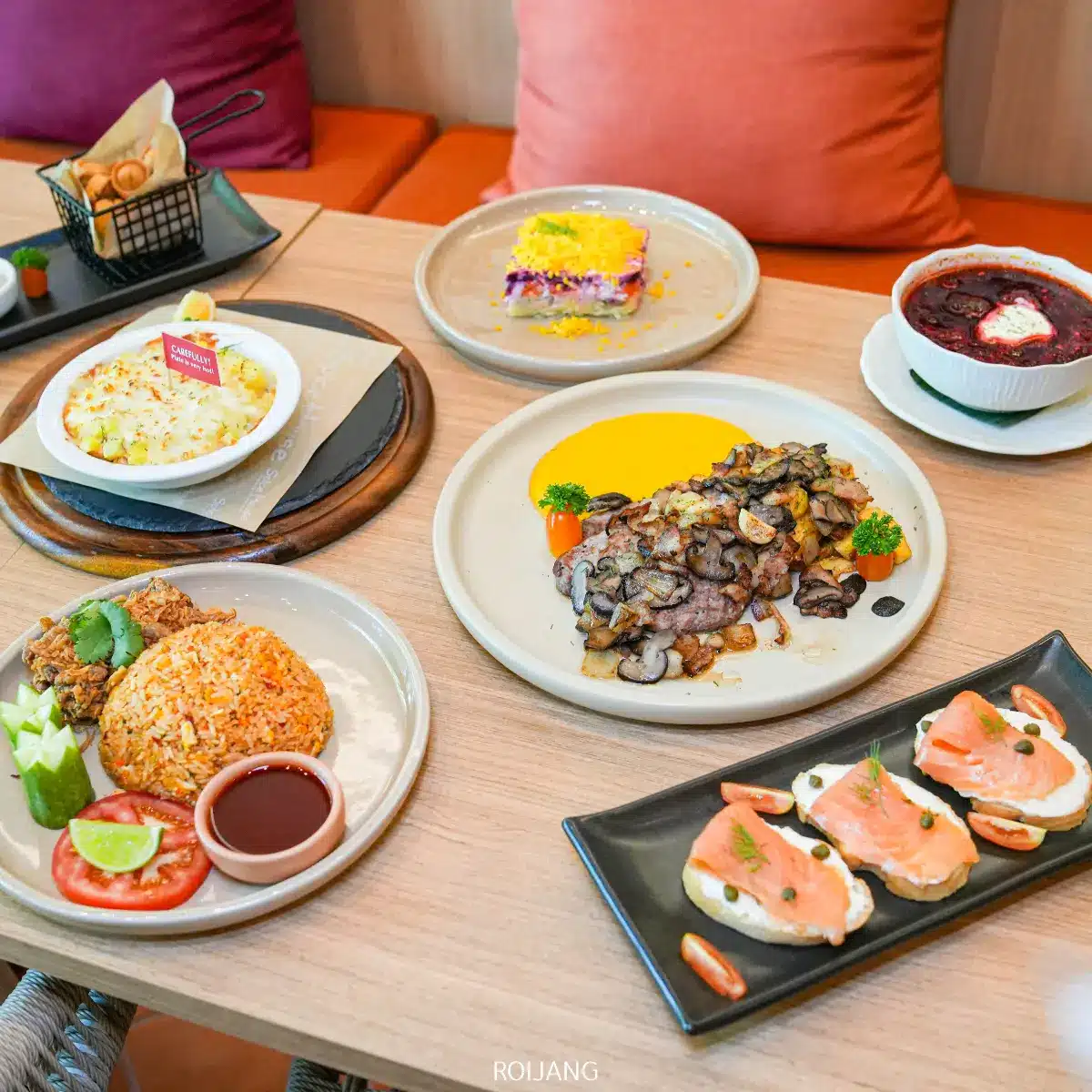 โต๊ะที่จัดเตรียมไว้ด้วยอาหารหลากหลายจาก Spice House รวมถึงอาหารเรียกน้ำย่อยแซลมอน เนื้อย่างราดซอส ข้าวไก่ทอด พาสต้าอบชีส ของหวานแบบหลายชั้น และของหวานเบอร์รี่.