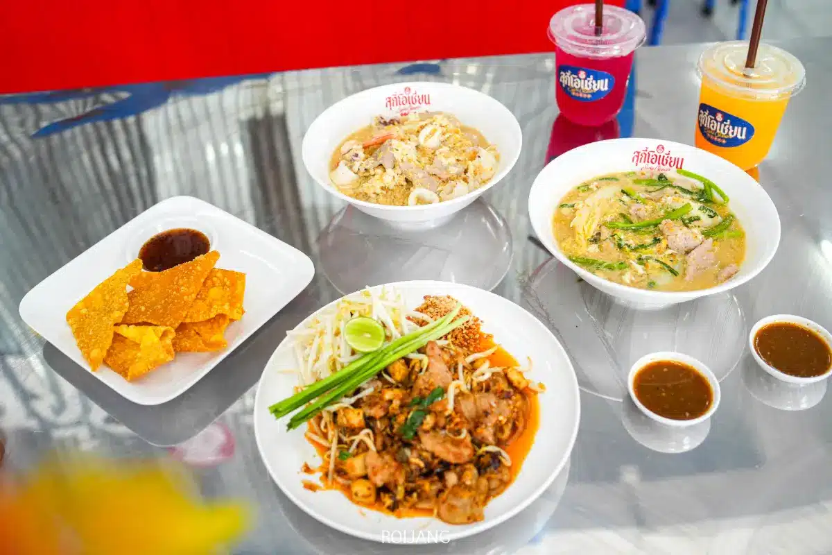 ขนมไทย 3 ชาม เกี๊ยวทอดราดซอส 1 จาน และเครื่องดื่ม 3 แก้ว วางอยู่บนโต๊ะโลหะสะท้อนแสงที่ร้านสุกี้โอเชี่ยน.