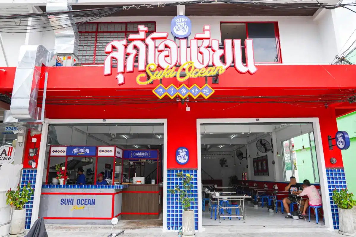 ร้านอาหารหน้าแดงชื่อสุกี้โอเชียน (สุกี้โอเชี่ยน) ที่นั่งแบบเปิดโล่ง โต๊ะสีฟ้า ลูกค้านั่งทานด้านใน.