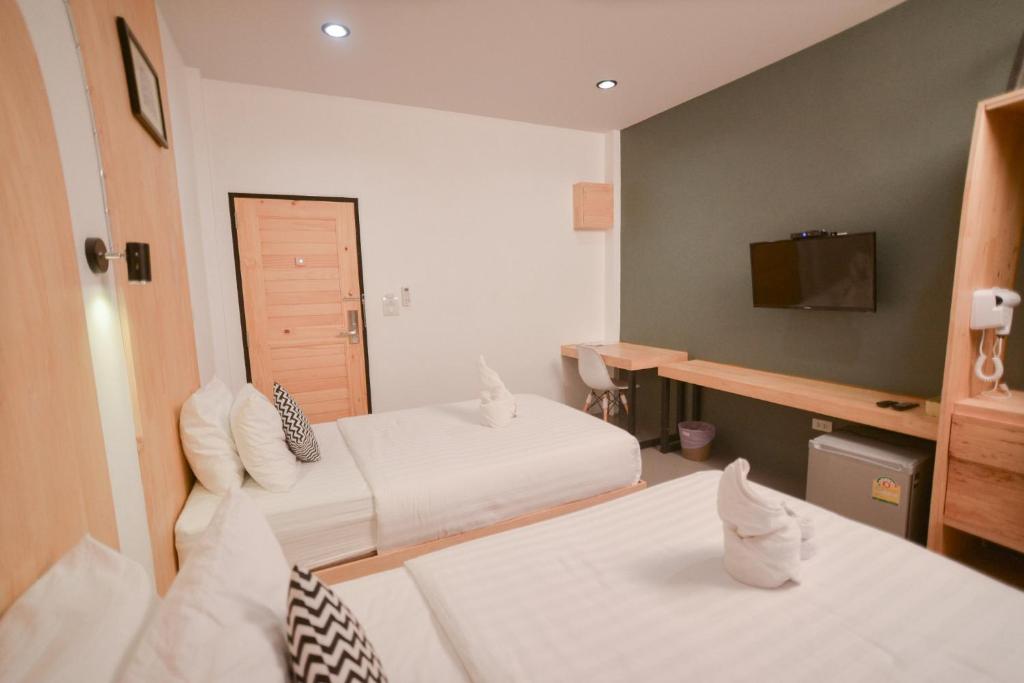 ห้องพักโรงแรมที่มีเตียงสองเตียงจัด เที่ยวเลย เรียงอย่างเรียบร้อย ทีวีติดผนัง โต๊ะพร้อมเก้าอี้ และตู้เย็นขนาดเล็ก—เหมาะสำหรับการพักผ่อนหลังจากสำรวจ ที่เที่ยวเลย พร้อมผ้าเช็ดตัวพับวางไว้บนเตียงแต่ละเตียงเพื่อความสะดวกสบายของคุณ.