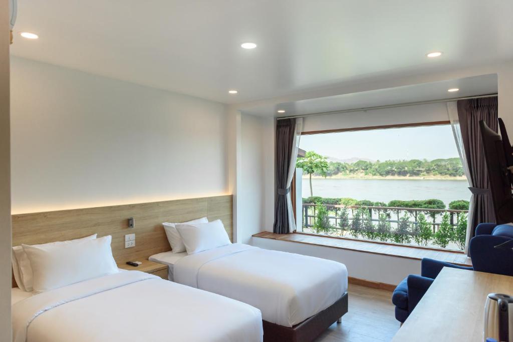 ห้องพักโรงแรมพร้อมเตียงเดี่ยวสองเตียง, ที่นั่งริมหน้าต่างขนาดใหญ่,  ที่เที่ยวเลย และวิวแม่น้ำที่สวยงาม—เหมาะสำหรับการผ่อนคลายหลังจากสำรวจสถานที่ท่องเที่ยวในจังหวัดเลย และสถานที่ท่องเที่ยวที่ดีที่สุดใกล้เคียง. เฟอร์นิเจอร์สมัยใหม่และแสงสว่างจากธรรมชาติทำให้การเข้าพักของคุณสมบูรณ์แบบ.